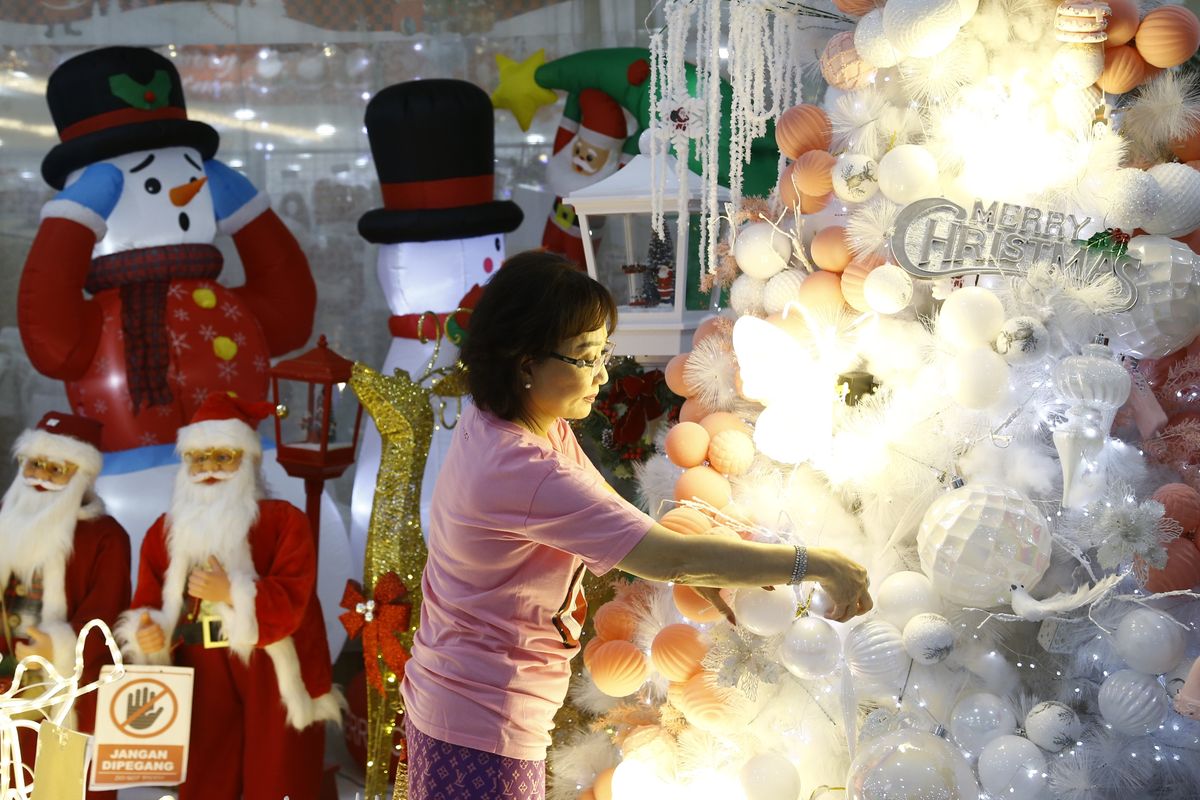 Saujani pemilik Sentosa Florist sedang menata pohon natal untuk menyambut Hari Natal 2025 di Pasar Atom Surabaya, Jawa Timur.