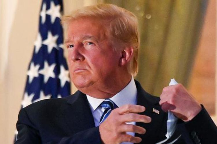 Presiden AS Donald Trump saat melepas masker setibanya di Gedung Putih, Senin (5/10/2020) malam waktu setempat.