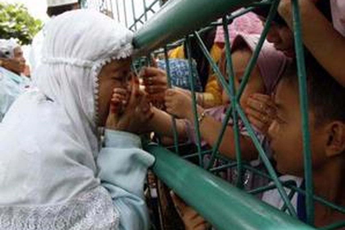 Seorang jemaah haji asal Kabupaten HSU, Kalimantan Selatan tak kuasa menahan tangis setelah tiba dan bertemu dengan sanak keluarga di pagar Asrama Embarkasi Haji Banjarmasin, Kalimantan Selatan, Minggu (14/12).