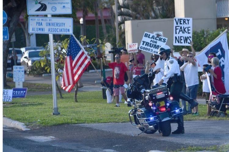 Sekelompok warga yang pro dan anti-Trump sama-sama menanti iring-iringan mobil kepresidenan melintas saat menuju ke resor Mar-a-Lago, Florida, Sabtu (25/11/2017).