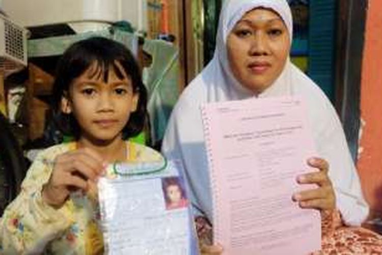 Annisa Tri Octaviani Andini (kiri) bersama ibunya, Juwariyah, di rumah mereka di Kelurahan Tugu Utara, Kecamatan Koja, Jakarta Utara, Sabtu (30/10), menunjukkan dokumen keikutsertaan Annisa dalam uji klinik vaksin dengue yang digagas Sanofi Pasteur. 