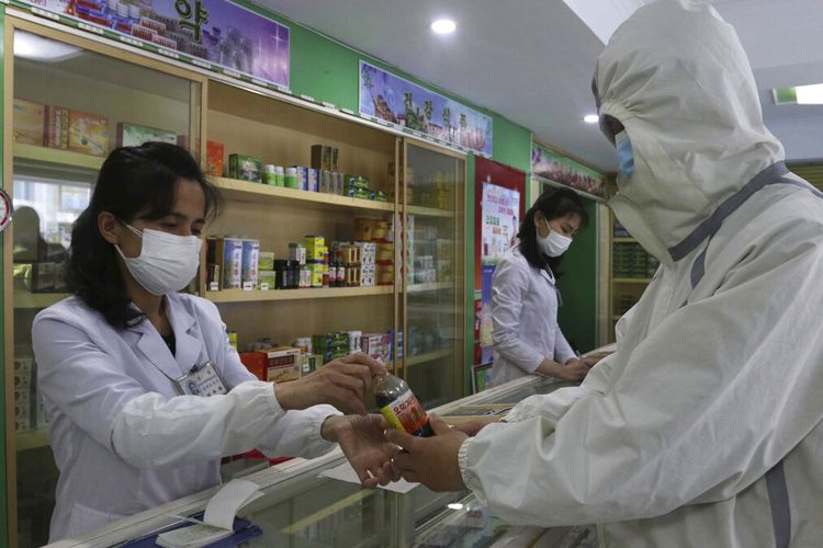 Seorang karyawan Kantor Manajemen Obat Distrik Daesong di Pyongyang memberikan obat kepada seorang penduduk saat negara meningkatkan langkah-langkah untuk menghentikan penyebaran penyakit di Pyongyang, Korea Utara, Senin, 16 Mei 2022. 