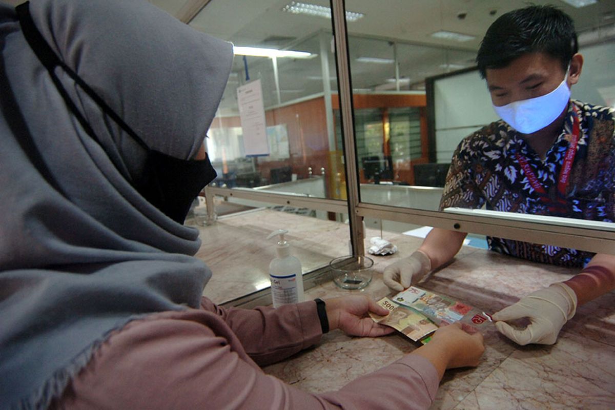 Petugas melayani warga transaksi penukaran uang baru pecahan Rp 75.000 saat penukaran Uang Peringatan Kemerdekaan 75 Tahun Republik Indonesia di Kantor Perwakilan (Kpw) Bank Indonesia (BI), Tegal, Jawa Tengah, Selasa (18/8/2020). Kpw BI Kota Tegal menyediakan sebanyak 1,3 juta lembar uang baru pecahan Rp 75.000 untuk ditukarkan warga dengan syarat daftar online dan menunjukkan KTP elektronik.