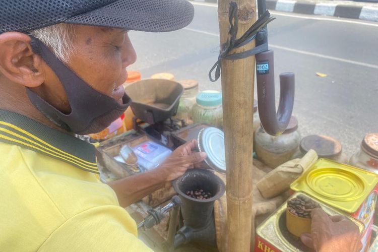 Suroso sedang menuang kopi untuk digiling di lapak miliknya yang terletak di sebelah Jembatan Mrican, Jalan Tentara Pelajar, Jomblang, Kecamatan Candisari, Kota Semarang, Kamis (2/11/2023).