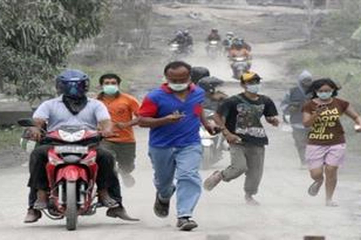 Villager run in volcanic ash in Argomulyo, Yogyakarta, Indonesia, Saturday, Nov. 6, 2010. A surge of searing gas raced down the sides of Mount Merapi at highway speeds Friday, setting houses and trees ablaze and blackening the bodies of those caught in its path.