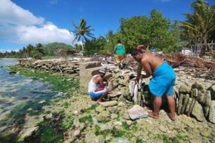 Foto ini menampilkan warga pulau Kiritimati, Kiribati tengah membangun tembok laut untuk mengurangi dampak ombak samudera Pasifik ke daratan. Kiribati adalah negara kepulauan kecil di Pasifik yang ketinggian rata-rata wilayah daratnya hanya beberapa meter di atas permukaan air laut. Akibat perubahan iklim, permukaan air laut meningkat dan membahayakan kehidupan di pulau-pulau kecil semacam Kiribati.