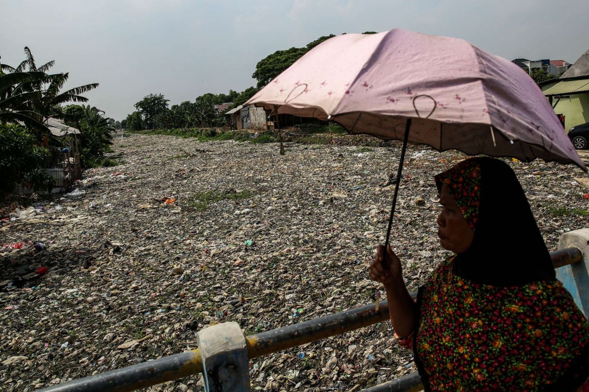 Warga melintas disamping sampah yang didominasi plastik di sepanjang Kali Pisang Batu, Desa Pahlawan Setia, Kecamatan Tarumajaya, Kabupaten Bekasi, Jawa Barat, Selasa (8/1/2019). Sampah yang memenuhi Kali Pisang Batu hingga sepanjang 1,5 kilometer berasal dari Kali Bekasi yang melewati Kota Bekasi. Sampah muncul pasca normalisasi dilakukan pada Desember 2018. Sebelumnya, kali hanya dipenuhi lumpur dan eceng gondok.