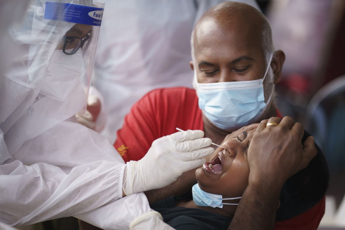 Petugas medis melakukan tes swab Covid-19 kepada seorang anak laki-laki di pusat pengujian Kajang, pinggiran Kuala Lumpur, Malaysia, pada Sabtu (8/5/2021).