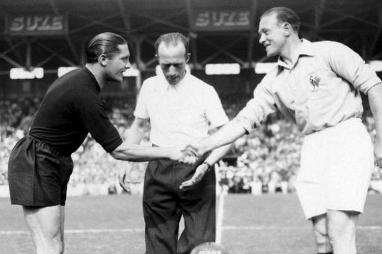 Kapten Italia, Giuseppe Meazza (kiri), berjabat tangan dengan kapten Perancis, Etienne Mattler, sebelum laga perempat final Piala Dunia 1938 di Stade olympique Yves-du-Manoir, Perancis. Pada laga tersebut, Italia mengenakan seragam tanding serba hitam atas perintah Benito Mussolini.
