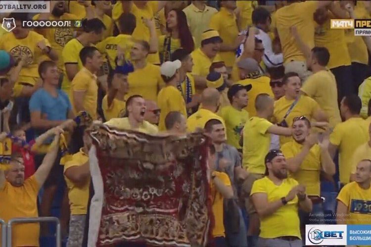 Seorang fans FC Rostov menyaksikan pertandingan timnya sambil membentangkan karpet, yang kemudian dijadikan motif kostum tim.