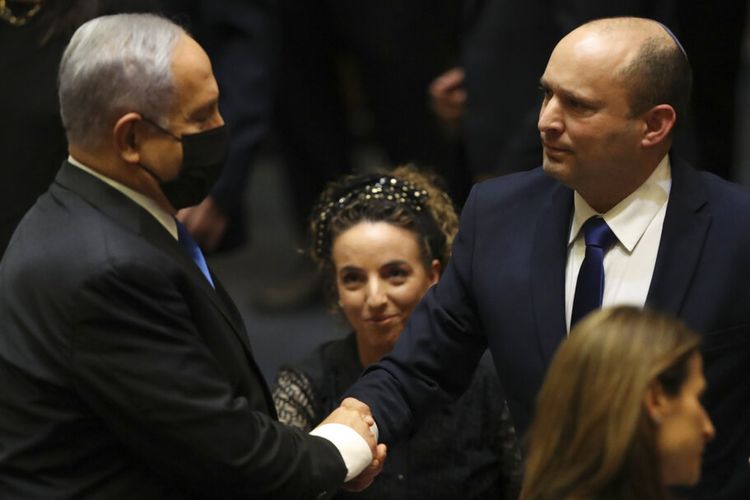 Perdana Menteri baru Israel Naftali Bennett berjabat tangan dengan Perdana Menteri Benjamin Netanyahu selama sesi Knesset di Yerusalem Minggu, 13 Juni 2021. 