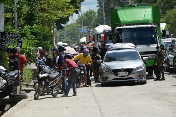 Aparat Kepolisian Filipina memeriksa barang bawaan warga di Kota Marawi, Rabu (24/5/2017). di mana pecah pertempuran antara kelompok bersenjata dan pasukan keamanan pada Selasa sore (23/5/2017).  