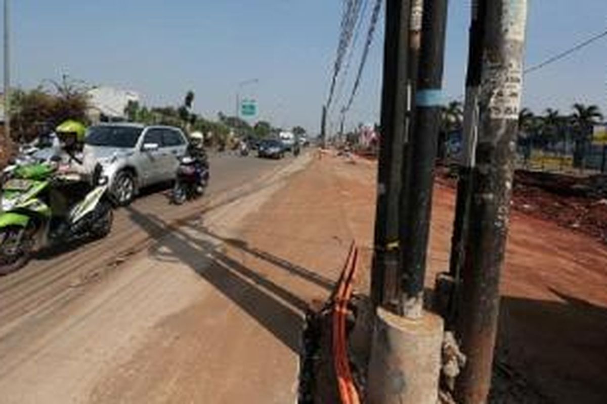 Ruas jalan inspeksi saluran Kalimalang di kawasan Duren Sawit, Jakarta Timur, yang sedang dilebarkan menyisakan jaringan utilitas di tengah jalan, Kamis (9/7). Jalan tersebut menjadi salah satu jalan utama bagi pemudik, khususnya pengendara sepeda motor, yang akan meninggalkan Jakarta.