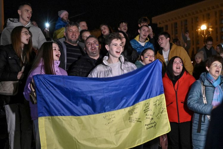 Warga memegang bendera Ukrania saat mereka berkumpul di alun-alun Maidan untuk merayakan pembebasan Kota Kherson pada Jumat (11/11/2022). Presiden Ukraina Volodymyr Zelensky mengatakan pada 11 November bahwa Kota Kherson berhasil direbut setelah Rusia mengumumkan selesainya penarikannya dari ibu kota wilayah Kherson.