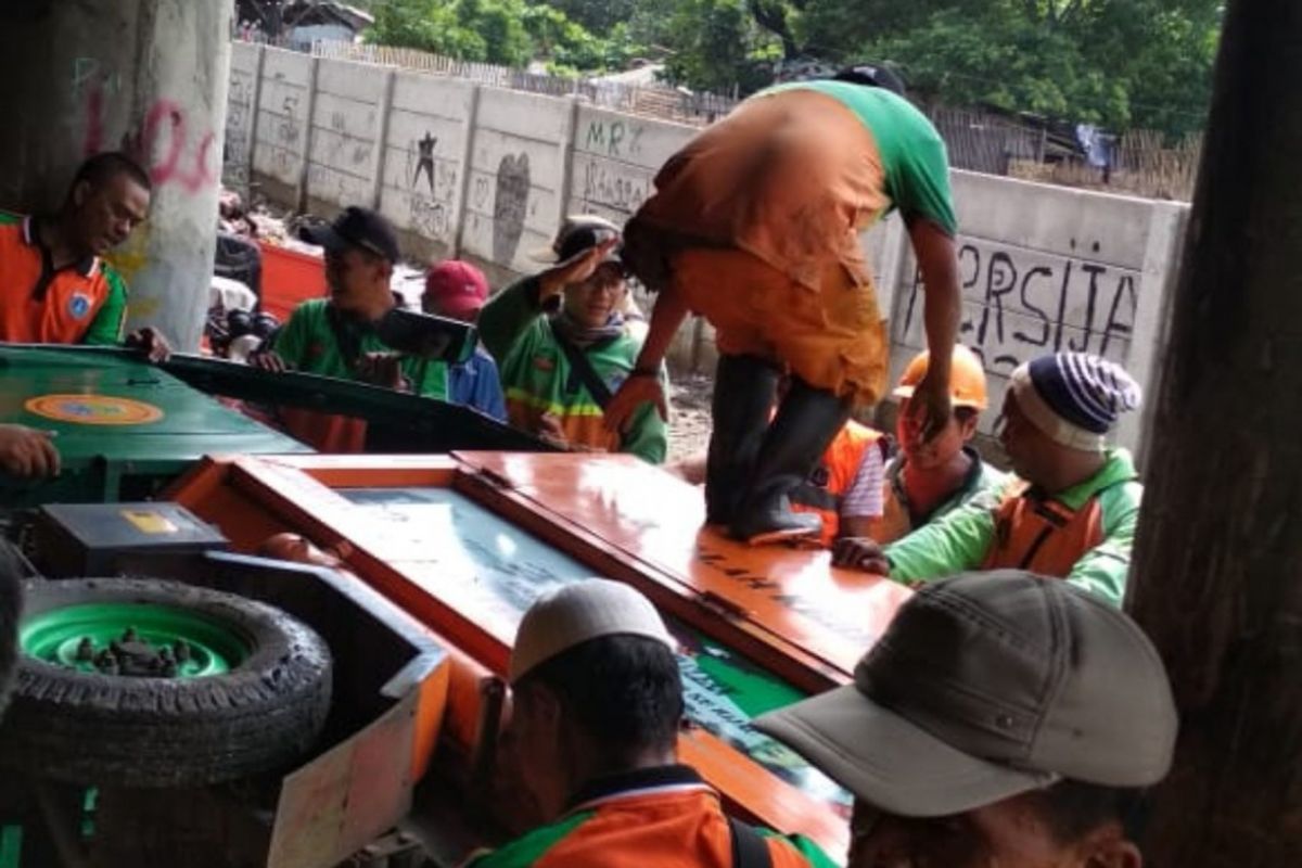 Petugas berupaya mengevakuasi gerobak motor yang terbalik saat membersihkan kolong tol Wiyoto Wiyono, Selasa (15/1/2019).