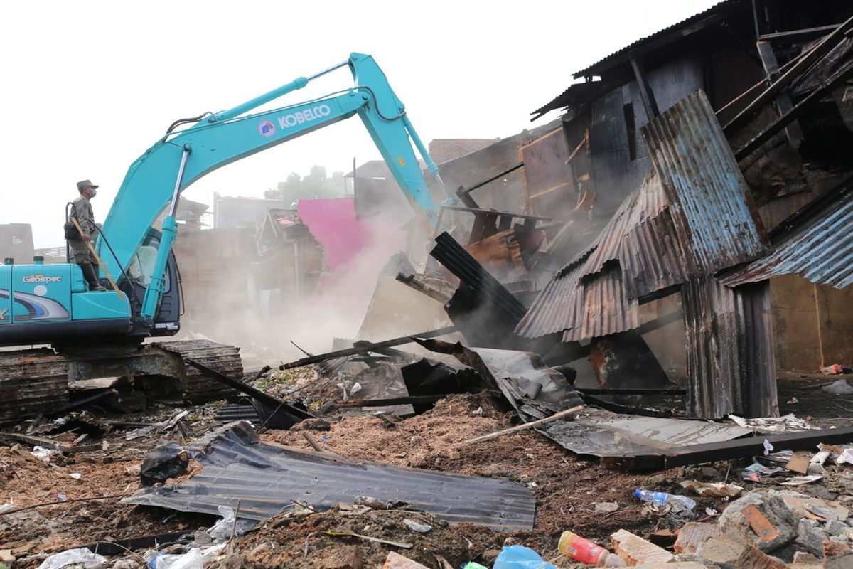 Petugas Satpol PP melalui dua back hoe membongkar bangunan semi permanen yang berada di area bantaran aliran Sungai Ciliwung di RW 01 Bukit Duri, Jakarta Selatan, Selasa (11/7/2017). Setelah bangunan diratakan dengan tanah, Balai Besar Sungai Ciliwung Cisadane (BBWSCC) akan memulai memasang sheet pile sebagai lanjutan proyek normalisasi Ciliwung.