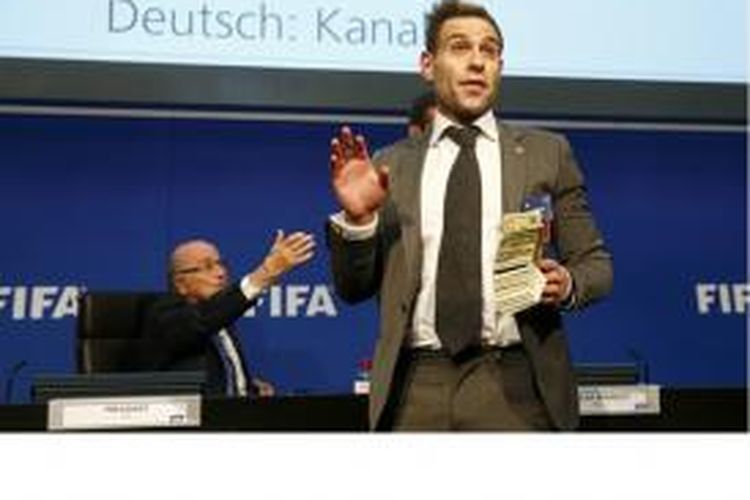 Komedian Inggris, Simon Brodkin, maju ke podium sebelum melempar Sepp Blatter dengan uang dollar AS palsu.