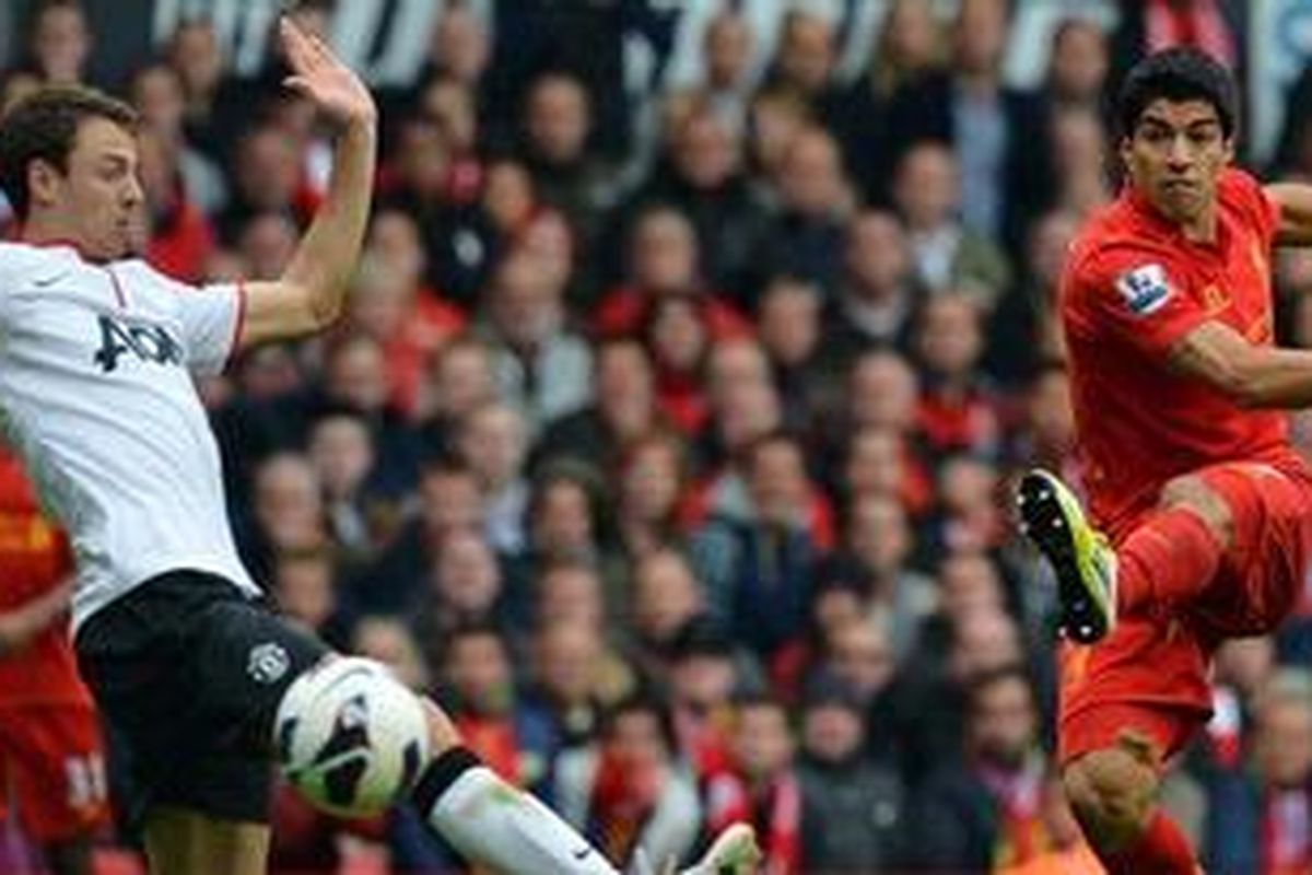 Bomber Liverpool dari Uruguay, Luis Suarez (kanan), menembak bola melewati hadangan bek Manchester United dari Irlandia Utara, Jonny Evans, dalam laga pekan kelima Premier League di Stadin Anfield, Minggu (23/9/2012). Liverpool akhirnya ditundukkan MU 1-2.