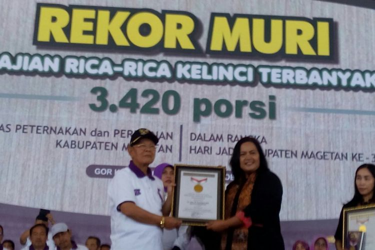 Executive Manager Museum Rekor Dunia Indonesia (Muri), Sri Widayati menyerahkan piagam pemecahan rekor Muri melalui penyajian kuliner rica-rica kelinci terbanyak kepada Bupati Magetan, Sumantri, Selasa ( 3/10/2017).