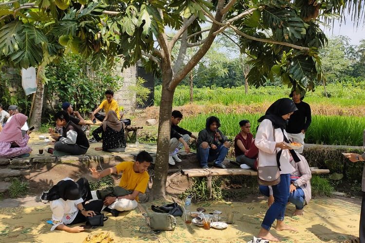 Para pengunjung duduk lesehan di tepi sawah Warung Kopi Klotok, Sleman Yogyakarta, Rabu (22/1/2020). Pengunjung bisa duduk di dalam rumah joglo maupun di luar dengan cara lesehan tikar.