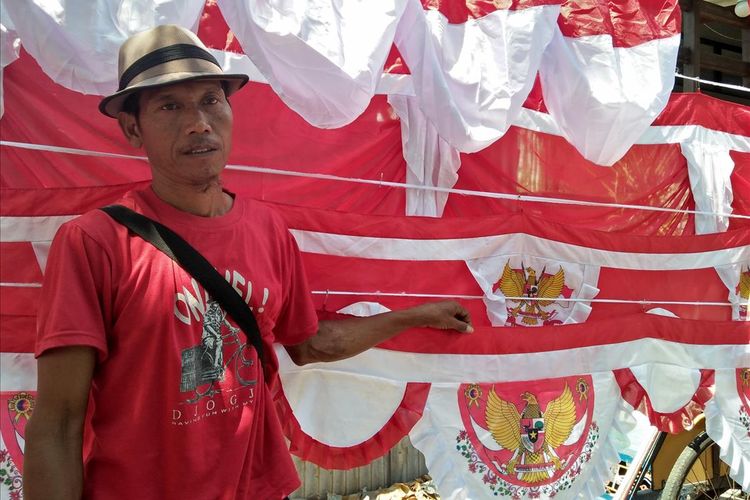 Maman bersama bendera dan pernak-pernik momen peringatan Hari Kemerdekaan 17 Agustus yang dijualnya. Dia datang dari Garut di Jabar ke Gresik di Jatim untuk menjual bendera milik juragannya. Upahnya Rp 2.500 per bendera terjual. Selama enam hari di Gresik dia baru menjual tiga bendera.