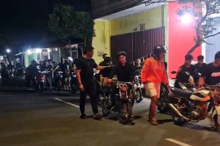 Para pemuda yang terjaring akan melakukan aksi balap liar di Jalan Soekarno - Hatta, Tuban, Jawa Timur, dipaksa petugas kepolisian untuk mendorong sepeda motornya menuju Mapolres Tuban, Minggu (15/6/2025).