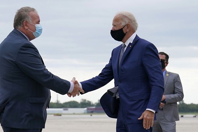 Kandidat presiden dari Partai Demokrat Joe Biden berjabat tangan dengan staf khusus Brian McParlin, setelah dia tiba di Bandara Internasional General Mitchell di Milwaukee, pada 3 September 2020.