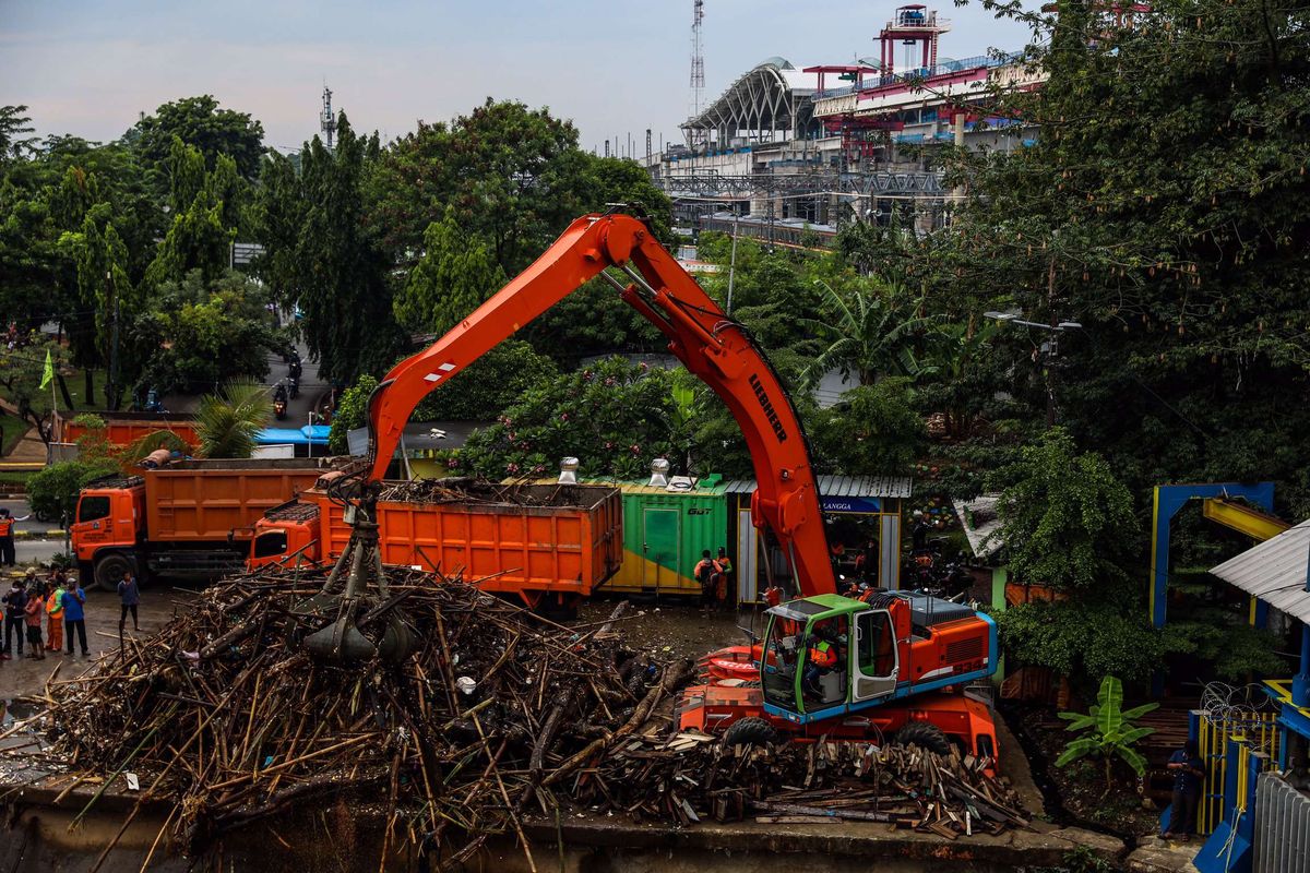 Petugas kebersihan DKI Jakarta mengangkut sampah yang terbawa arus menggunakan alat berat di Pintu Air Manggarai, Jakarta Pusat, Selasa (22/9/2020). Kenaikan muka air di Pintu Air Manggarai diakibatkan oleh hujan yang mengguyur kota Bogor dan Jakarta mulai Senin malam (21/9/2020) selama beberapa jam.