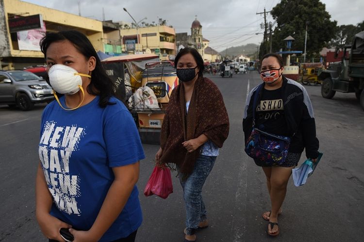 Warga lokal mengenakan masker untuk melindungi mereka dari abu vulkanik akibat meletusnya gunung Mayon.