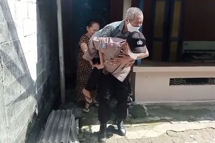 Aipda Giyanto anggota Bhabinkamtibmas Polsek Sukoharjo Kota menggendong warga lansia untuk divaksin Covid-19.