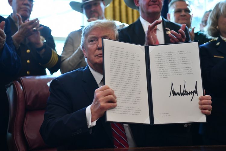 Presiden AS Donald Trump menunjukkan perintah eksekutifnya berisi veto menolak resolusi yang disahkan Senat untuk membatalkan status darurat nasional guna membiayai tembok perbatasan pada Jumat (15/3/2019).