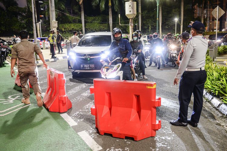 Petugas gabungan menutup akses jalan menuju Bundaran Hotel Indonesia dari Jalan Imam Bonjol, Jakarta, Jumat (31/12/2021). Polda Metro Jaya memberlakukan pengendalian mobilitas Crowd Free Night (malam bebas keramaian) pada malam tahun baru 2022 yang berlangsung mulai pukul 22.00 - 04.00 WIB.