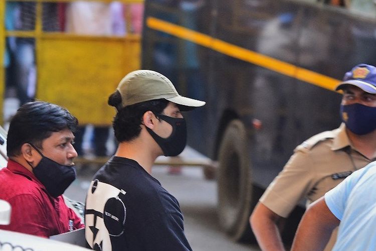 Putra aktor Bollywood Shah Rukh Khan, Aryan Kan (tengah) digiring aparat kepolisian di luar Biro Pengendalian Narkotika (NCB/Narcotics Control Bureau) d Mumbai, Minggu (3/10/2021). Dia diperiksa bersama beberapa orang menyusul penggerebekan di sebuah pesta di kapal pesiar.