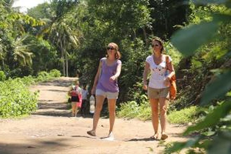Wisatawan asing sedang berjalan di jalan tanah tidak jauh dari kawasan menuju Pantai Bias Putih di Candidasa, Karangasem, Bali.