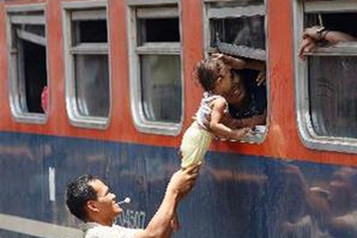 Naik Lewat Celah Pintu - Calon penumpang Kereta Api Kertajaya jurusan Jakarta Pasar Senen-Surabaya Pasar Turi memasukkan anaknya ke dalam gerbong lewat jendela gerbong, Jumat (7/10). Pada hari itu jumlah pemudik dari Stasiun Pasar Senen mulai meningkat drastis. 