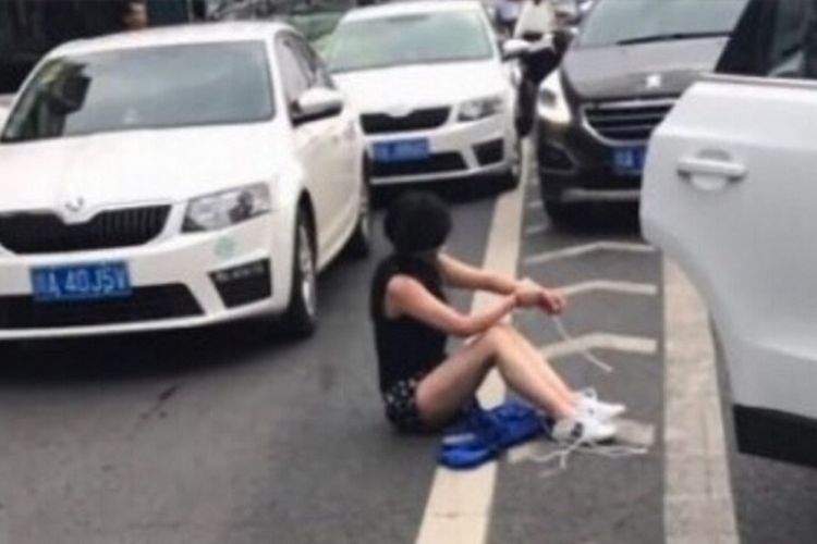 Dalam foto ini terlihat perempuan korban penculikan yang terduduk di jalanan setelah mobil penculiknya terlibat tabrakan.