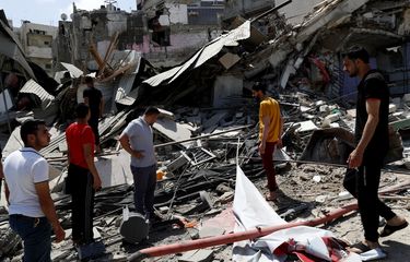 Orang-orang memeriksa puing-puing dari bangunan yang hancur akibat serangan udara Israel di Gaza, pada Kamis (20/5/2021).