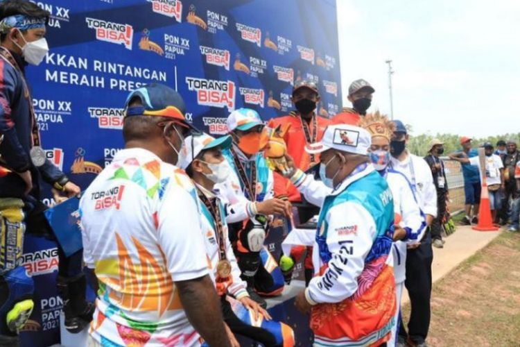 Gubernur Papua Lukas Enembe menyerahkan medali emas kepada atlet Papua pemenang kelas modifikasi beregu PON Papua di Sirkuit Balap Motor Tanah Miring, Merauke
