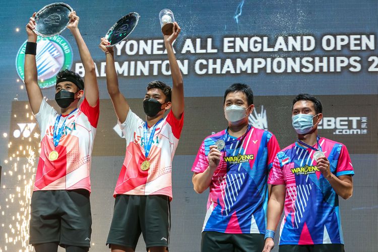 Ganda Putra Indonesia Muhammad Shohibul Fikri (kiri) dan Bagas Maulana (kedua kiri) disaksikan pasangan Hendra Setiawan (kedua kanan) dan Muhammad Ahsan mengangkat trofi juara usai laga final nomor ganda putra All England di Utilita Arena Birmingham, Inggris, Minggu (20/3/2022). Bagas/Fikri berhasil menjadi juara All England 2022 setelah mengalahkan ganda putra Indonesia lainnya Muhammad Ahsan - Hendra Setiawan dengan skor 21-19 dan 21-13.