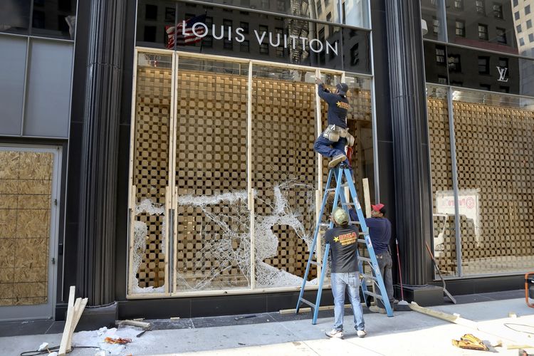 Para pekerja memperbaiki etalase di gerai Louis Vuitton yang dirusak massa, dalam aksi kerusuhan dan penjarahan di kota Chicago, Amerika Serikat, Senin (10/8/2020). Kerusuhan terjadi di sepanjang kompleks pertokoan elite bernama Magnificent Mile.