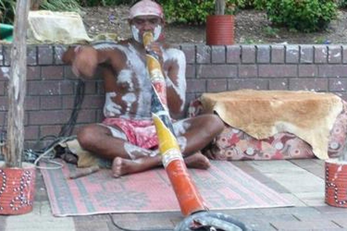 Wilson, pemuda asli aborigin ini memainkan alat musik asli sukunya, didgeridoo, di tengah keramaian koridor jalan antara Jembatan Harbour dengan Opera House, Sydney.