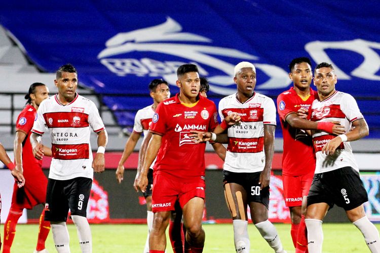 Pemain muda Persija Jakarta Taufik Hidayat divaga ketat pemain Madura United Hugo Gomez pada laga tunda pekan 21 Liga 1 2021-2022 yang berakhir dengan skor 1-3 di Stadion Kapten I Wayan Dipta Gianyar, Kamis (17/3/2022) malam.