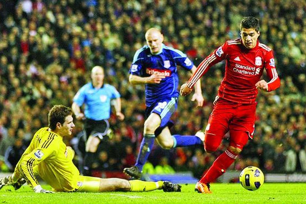 Striker baru Liverpool, Luis Suarez (kanan), mengecoh penjaga gawang Stoke City, Asmir Begovic, dan mencetak gol pada laga Liga Inggris di Stadion Anfield, Liverpool, Inggris, Rabu (2/2).