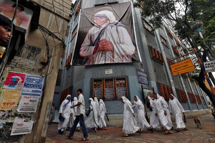 Para biarawati yang tergabung dalam Missionaries of Charity (MoC) global, berjalan melewati spanduk besar Bunda Teresa menjelang upacara kanonisasinya, di Kolkata, India pada 3 September 2016. /