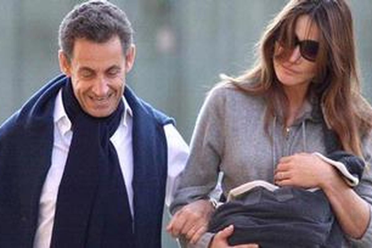 Presiden Prancis Nicolas Sarkozy dan istrinya Carla Bruni yang menggendong putri pertama mereka, Giulia, di Versailles, Prancis.