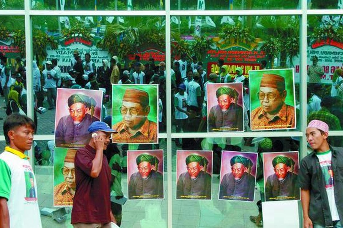 Simpatisan Partai Kebangkitan Bangsa (PKB) di depan poster Ketua Dewan Syuro DPP PKB KH Abdurrahman Wahid (Gus Dur) dan poster pendiri Nahdlatul Ulama KH Hasyim Asyari pada deklarasi pencalonan Gus Dur sebagai presiden pada Pemilu 2009 di Surabaya, Minggu (24/2). Deklarasi dihadiri ribuan kader PKB.  