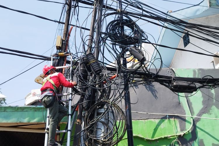 Teknisi Telkom meninjau kondisi kabel semrawut di Jalan Cikini IV, Menteng, Jakarta Pusat, Selasa (8/8/2023). (KOMPAS.com/XENA OLIVIA)