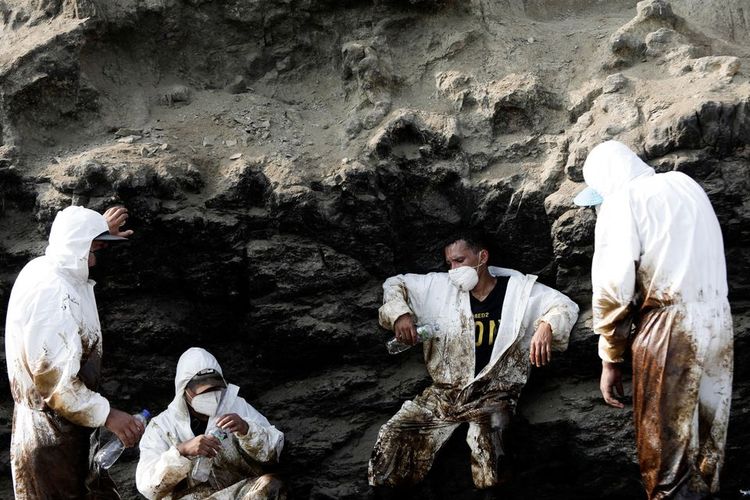 Pekerja beristirahat setelah membersihkan tumpahan minyak yang disebabkan oleh gelombang abnormal, yang dipicu oleh letusan gunung berapi bawah laut besar-besaran di Tonga, lepas pantai Lima, di Ventanilla, Peru, Rabu (19/1/2022). 