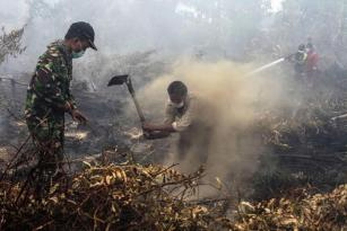Warga dan tentara berupaya memadamkan kebakaran lahan ladang di Rimbo Panjang, Provinsi Riau, 6 September 2015. Kebakaran hutan disebabkan oleh pembersihan lahan secara ilegal di Sumatera dan kalimantan.