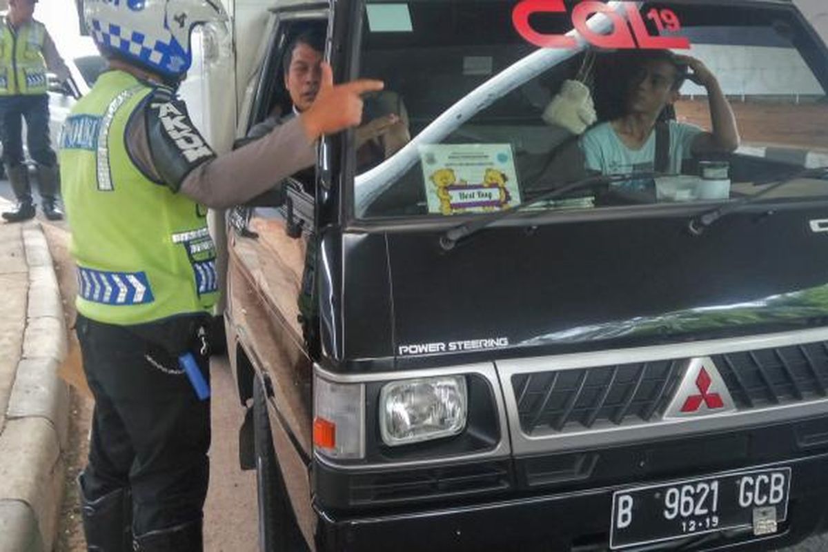 Petugas kepolisian sedang memberikan sanksi tilang kepada pengemudi kendaraan berpelat nomor ganjil di kolong flyover Kuningan pada Selasa (30/8/2016).
